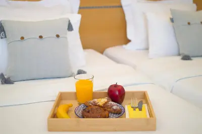 a tray of food and an apple and orange juice on a bed at Acropol Hotel in Athens