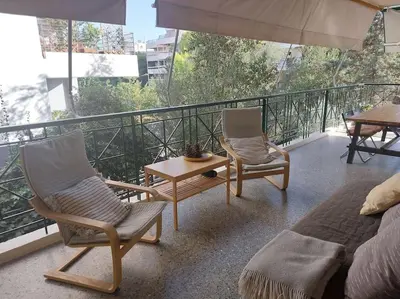 a balcony with two chairs and a table and a couch at quiet apartment with a large balcony near the sea in Athens