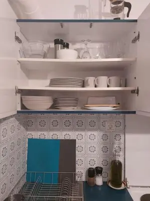 a kitchen with plates and dishes on shelves at quiet apartment with a large balcony near the sea in Athens