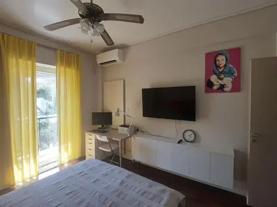 a bedroom with a bed and a flat screen tv at quiet apartment with a large balcony near the sea in Athens