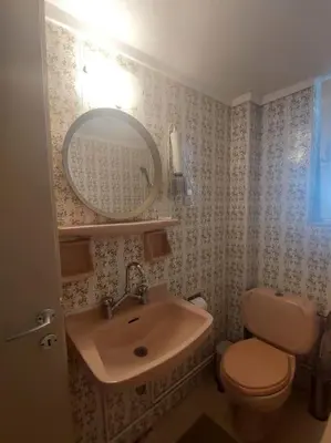 a bathroom with a sink and a toilet and a mirror at quiet apartment with a large balcony near the sea in Athens