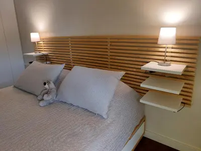a teddy bear sitting on a bed with two pillows at quiet apartment with a large balcony near the sea in Athens