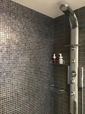 a bathroom with a shower with black tiles at NATURE & SEA in Saronida