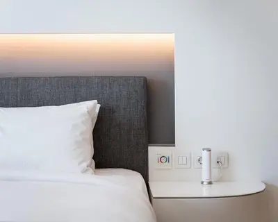 a bed with a white pillow and a table with a lamp at Mirada Hotel in Athens