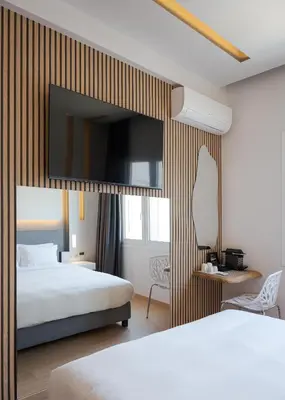 a hotel room with two beds and a mirror at Mirada Hotel in Athens