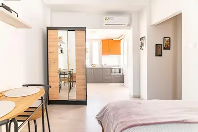 a room with a bed and a table and a kitchen at Under the Hill in Athens