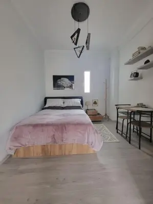 a white bedroom with a bed and a table at Under the Hill in Athens