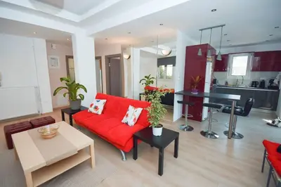 a living room with a red couch and a table at Cozy Cloud Apartment in Markopoulo