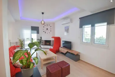 a living room with a couch and a red chair at Cozy Cloud Apartment in Markopoulo