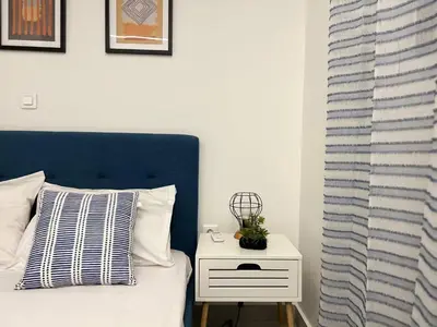 a bed with a blue headboard and a white night stand at Attiki Apartment VIPGreece in Athens