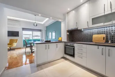 a kitchen with white cabinets and a dining room at Spacious & bright 2br apt in hip Pangrati, Athens in Athens