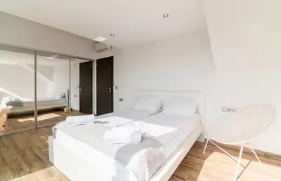 a white bedroom with a bed and a chair at Villa Azzura with sea view & private pool at Athens Riviera in Aghia Marina
