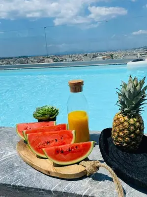 a plate of watermelon and a bottle of juice and a pineapple at New 2BD aprt with Shared Rooftop Pool D3 in Athens