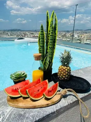 a plate of watermelon and a bottle of juice and a pineapple at New 2BD aprt with Shared Rooftop Pool D3 in Athens