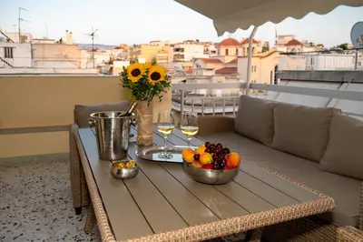 a table with fruit and wine glasses on a balcony at Acropolis Terrace View Apartment in Athens