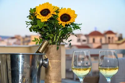 two glasses of white wine and a vase with sunflowers at Acropolis Terrace View Apartment in Athens