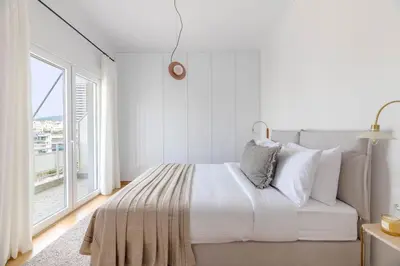 a white bedroom with a bed and a large window at Flawless 1BR Apartment in Athens by UPSTREET in Athens