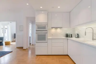 a white kitchen with white appliances and a wooden floor at Flawless 1BR Apartment in Athens by UPSTREET in Athens