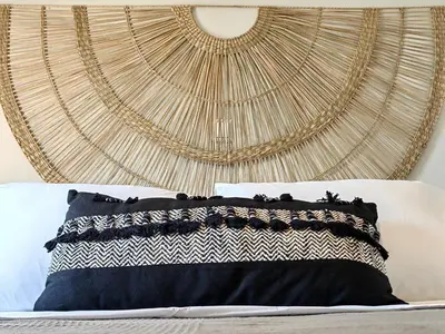 a bed with a black and white pillow in front of a wall at Funky Boho Kallithea Loft in Athens