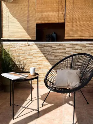 a chair sitting next to a table with a cup at Funky Boho Kallithea Loft in Athens