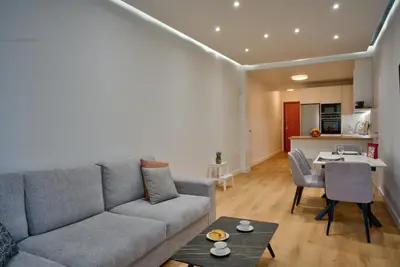 a living room with a couch and a table and a kitchen at The Cosy luxurious Seaside Apartment in Athens