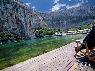 a person sitting on a bench on a wooden dock next to the water at Relux Sea View 2 Bedroom Apartment by BluPine in Athens