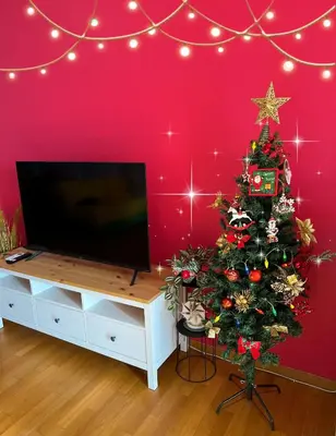 a christmas tree in a room with a red wall at Cozy fairytal garden apartment, Family Friendly, Free parking, 15 Min to Airport in Athens