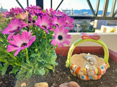 a basket with a bunny in it next to flowers at Cozy fairytal garden apartment, Family Friendly, Free parking, 15 Min to Airport in Athens