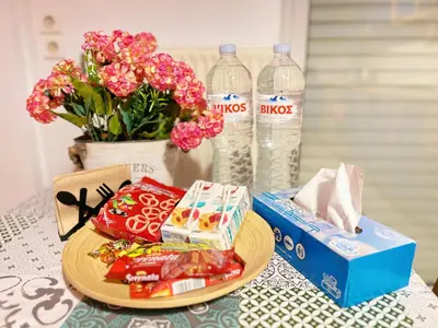 a table with a plate of food and flowers and water bottles at Cozy fairytal garden apartment, Family Friendly, Free parking, 15 Min to Airport in Athens