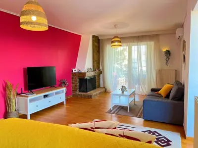 a living room with a yellow couch and a pink wall at Cozy fairytal garden apartment, Family Friendly, Free parking, 15 Min to Airport in Athens