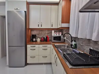 a kitchen with white cabinets and a refrigerator at Keti's home in Athens