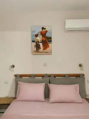 a bed with two pink pillows and a painting on the wall at Keti's home in Athens