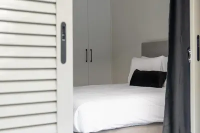 a bedroom with a white bed with a black pillow at Greyt Apartments Glyfada in Athens