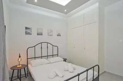 a white bedroom with a bed and a table at Sofia's Home Piraeus Modern, Reno, Fully Equipped in Piraeus