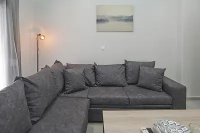 a grey couch in a living room with a table at Sofia's Home Piraeus Modern, Reno, Fully Equipped in Piraeus