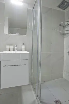 a white bathroom with a shower and a sink at Sofia's Home Piraeus Modern, Reno, Fully Equipped in Piraeus