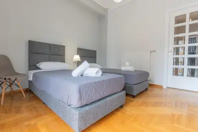 two beds in a white room with wooden floors at Athens Oasis - Timeless comfort at the Acropolis in Athens