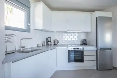 a white kitchen with a sink and a refrigerator at Villa Tholos -Athens Riviera in Kalívia Thorikoú