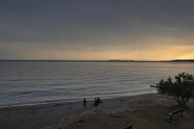 two people standing on the beach at sunset at House in riviera lagonisi in Kalívia Thorikoú