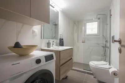 a white bathroom with a washing machine in it at Athens Gem in Koukaki in Athens