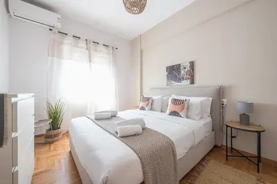 a white bedroom with a large bed and a window at Athens Gem in Koukaki in Athens