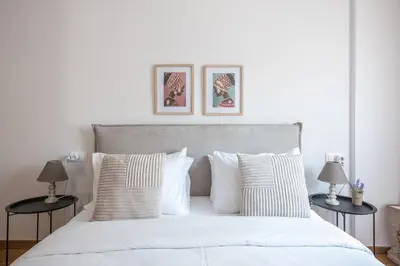 a white bed with white pillows and two tables at Athens Gem in Koukaki in Athens
