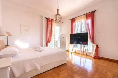 a bedroom with a bed and a flat screen tv at Villa Antiope Saronida in Saronida
