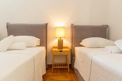 two beds in a room with a lamp on a table at Villa Antiope Saronida in Saronida