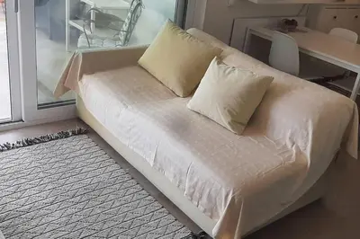 a white couch with pillows sitting in front of a window at Το σπίτι του καπετάνιου στη Βουλιαγμένη in Athens