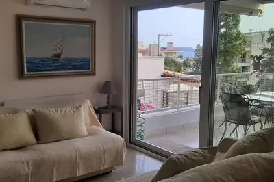 a living room with a couch and a view of a balcony at Το σπίτι του καπετάνιου στη Βουλιαγμένη in Athens