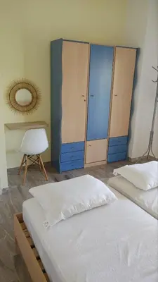 two beds in a room with blue cabinets and a chair at Euphoria Estate in Agia Marina Aegina