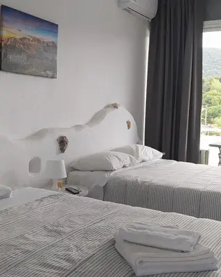 a hotel room with two beds and a window at BY THE SEA ROOMS, AVLAKI in Porto Rafti