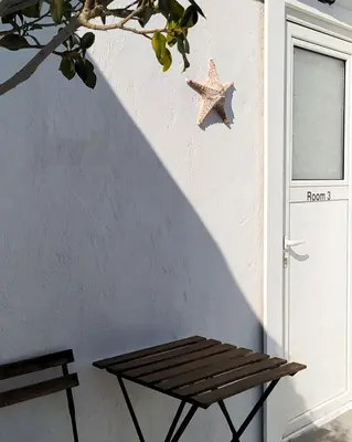 a wooden bench next to a door with a starfish on the wall at BY THE SEA ROOMS, AVLAKI in Porto Rafti