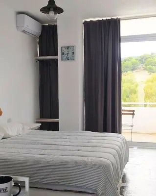 a bedroom with a bed and a large window at BY THE SEA ROOMS, AVLAKI in Porto Rafti